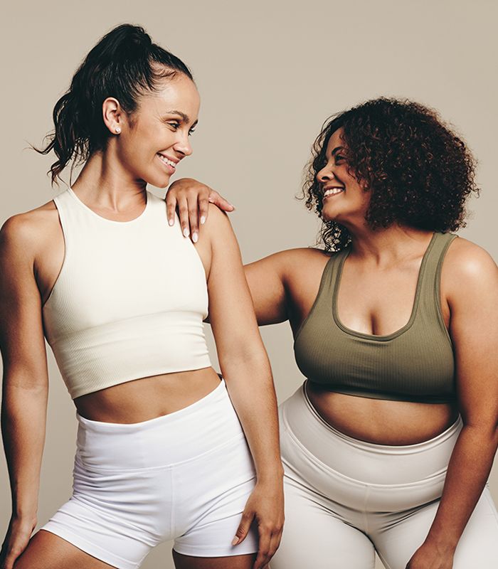 Two women smiling in athletic wear.