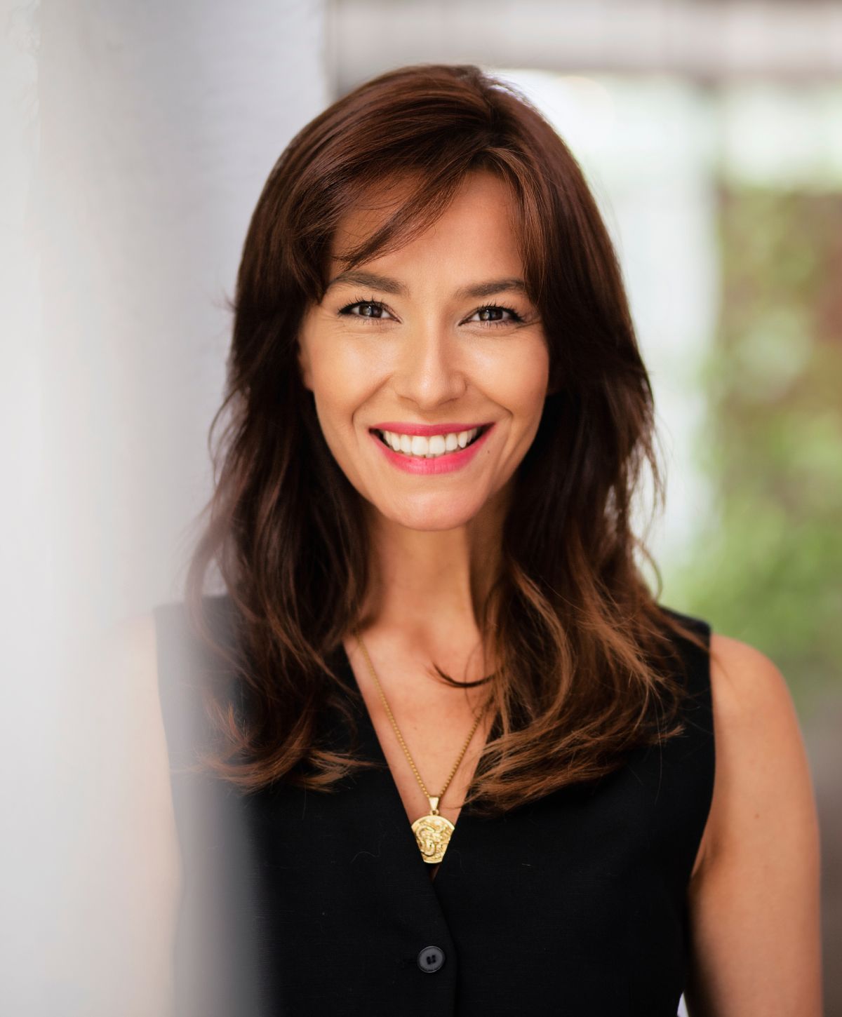 Smiling woman with long hair and necklace.