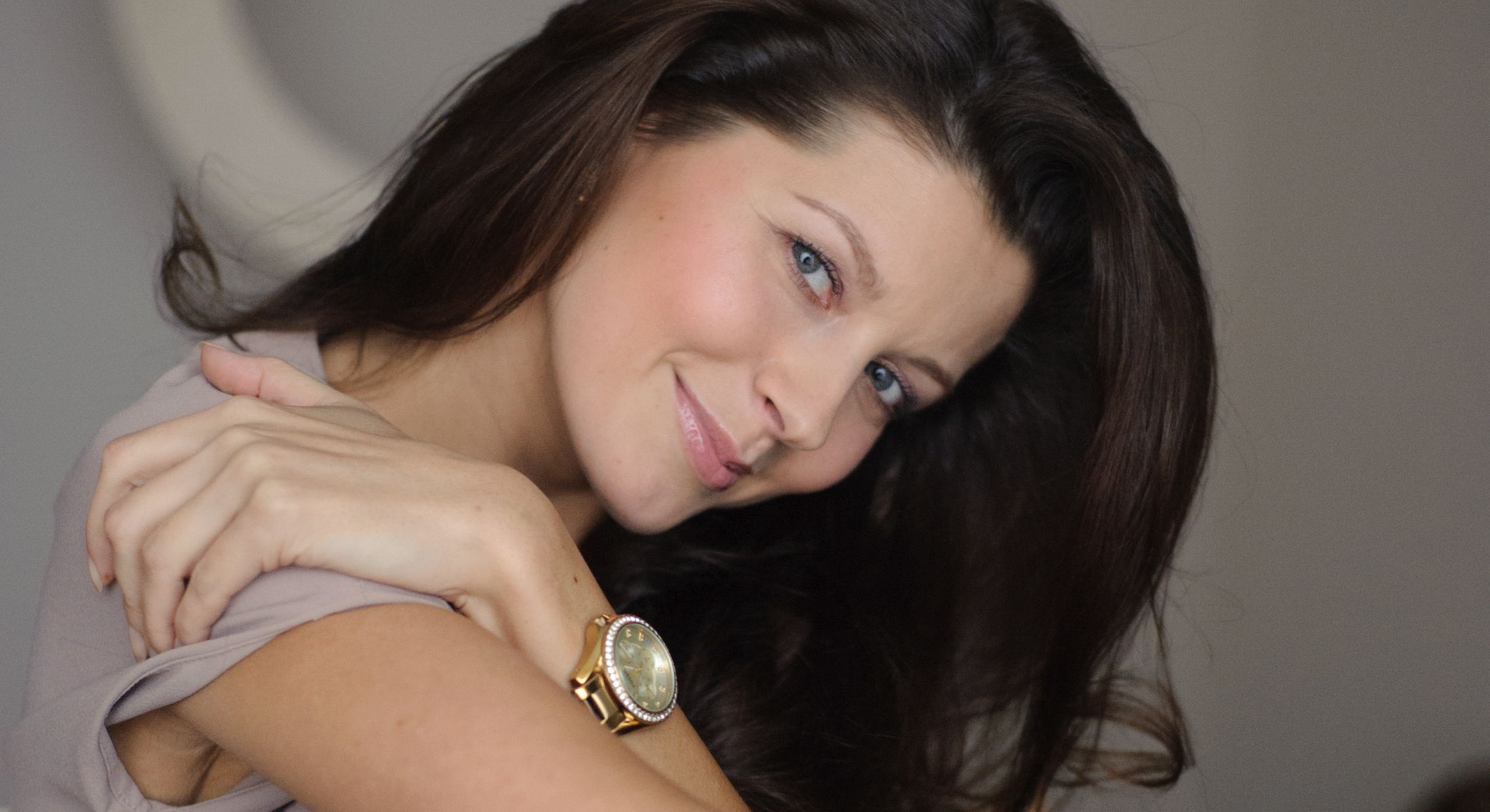 Smiling woman with long hair and a watch.